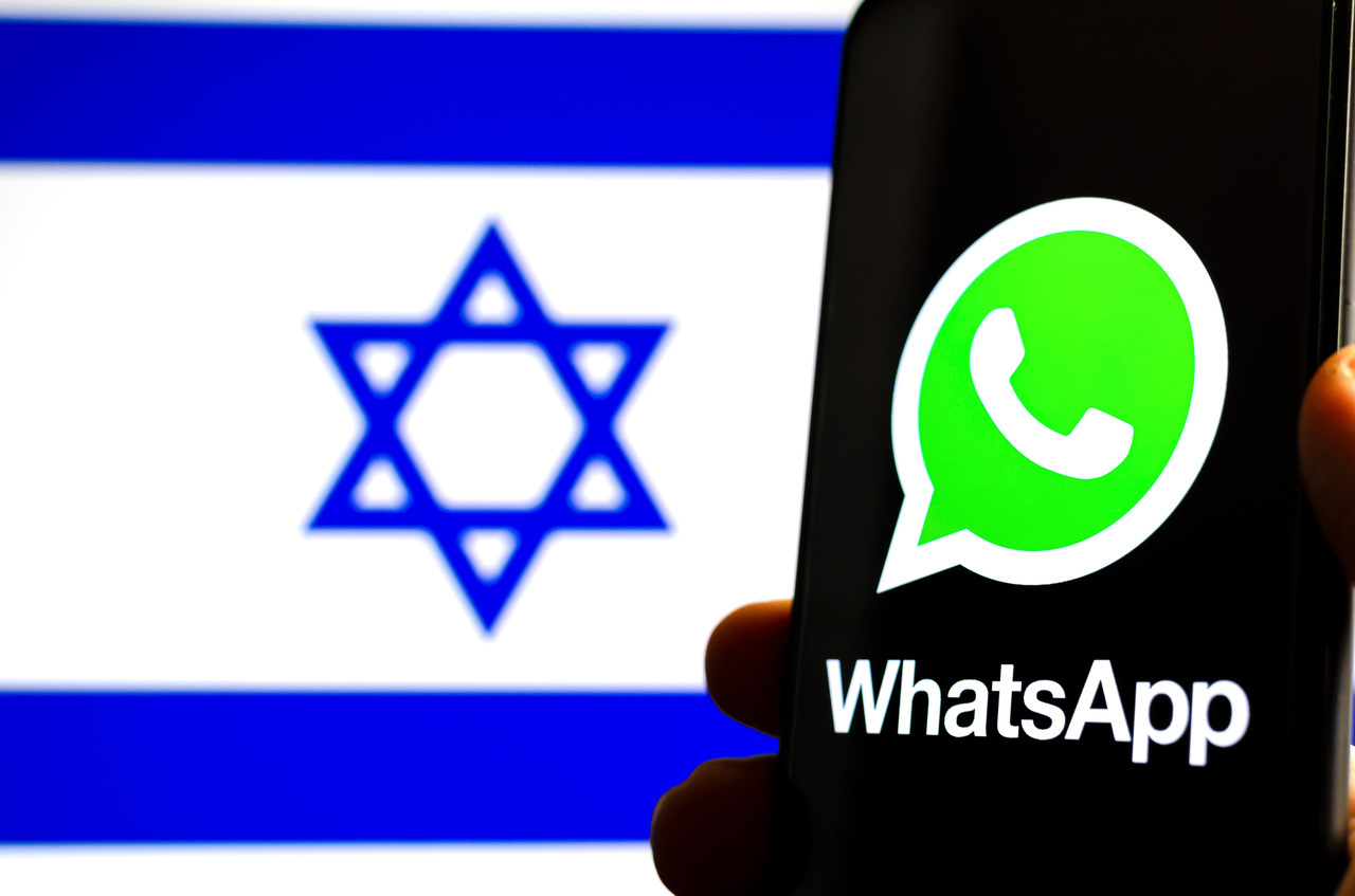 A smartphone displaying the WhatsApp logo before an Israeli flag